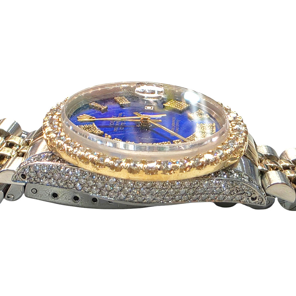 A rolex datejust featuring a gold-tone case with a diamond-encrusted bezel, a blue dial with gold hour markers, and a two-tone silver and gold-tone link bracelet heavily paved with diamonds, shown against a plain white background.