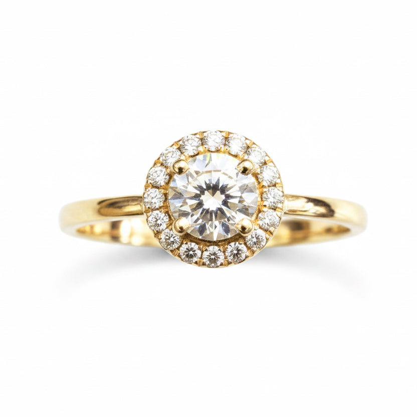 A yellow gold ring featuring a round-cut diamond center stone surrounded by a halo of smaller diamonds, set on a polished gold band against a white background.